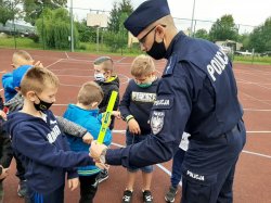 Policjant rozdaje odblaski dzieciom na zajęciach