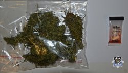 Zdjęcie przedstawia worek z zawartością zielonego suszu roślinnego leżącego na stole, obok znajduje się policyjny narkotest zawierający próbkę narkotyków