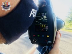policjant w maseczce mierzy prędkość przy użyciu fotoradaru