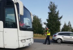 policjant kontroluje kierowce autobusu na poboczu drogi
