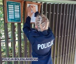 policjantka przyczepia na tablicy ogłoszeń ulotkę profilaktyczną o bezpieczeństwie podczas grzybobrania