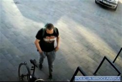 złodziej rowerowy podczas kradzieży roweru. Obraz nagrany kamerą monitoringu