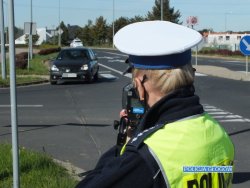 policjantka mierzy prędkość przejeżdżającego samochodu