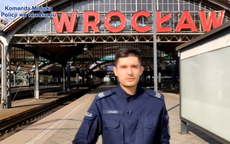Zdjęcie przedstawia policjanta w mundurze na tle Dworca Głównego we Wrocławiu.