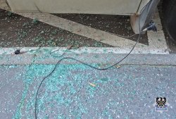 Na zdjęciu szkło rozbitej bocznej szyby samochodu leżąca na ziemi koło samochodu.