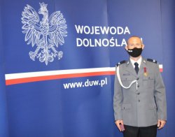 Na zdjęciu starszy sierżant Wiktor Fedorczuk stojący z odznaczeniem Brązowym Krzyżem Zasługi na tle baneru Wojewody Dolnośląskiego