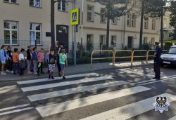 Na zdjęciu policjantka przeprowadza z dzieci przez przejście dla pieszych w trakcie działań Bezpieczna droga do szkoły w Mieroszowie.