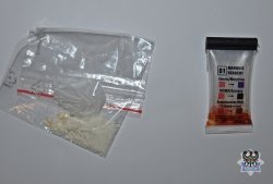 Na zdjęciu na biurku leży woreczek z zawartością białego proszku, obok znajduje się tester narkotykowy z brunatną cieczą w środku określającą substancję.