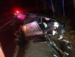 Zdjęcie zrobione w porze nocnej przedstawiające prawy uszkodzony bok pojazdu, który brał udział w wypadku drogowym.