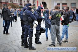 policjanci rozmawiają z uczestnikiem demonstracji w tle widać demonstrantów