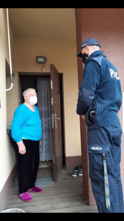 Policjant rozmawia przed domem ze starszą panią