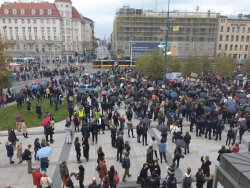 Tłum ludzi przed dworcem. Na środku placu stoi radiowóz z megafonem.