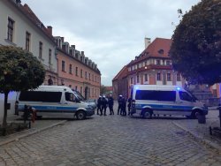 Dwa radiowozy i stojący przy nich umundurowani policjanci.