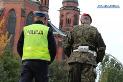 Na zdjęciu wspólny patrol policjant ruchu drogowego oraz funkcjonariusz Żandarmerii Wojskowej w tle kościół.