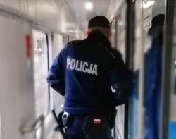 Na zdjęciu policjant idący przedziałem pociągu.