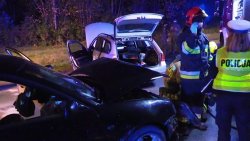 Na zdjęciu dwa uszkodzone samochody, które brały udział  w kolizji, pracująca na miejscu policjantka oraz dwaj strażacy.