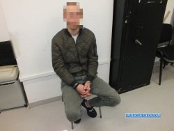 Na zdjęciu podejrzany w kajdankach siedzący na krześle w trakcie przesłuchania.
