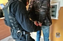 Na zdjęciu policjant zakłada kajdanki zatrzymanemu mężczyźnie.