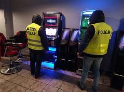 Na zdjęciu policjant i strażnik służby celnej stojący naprzeciwko dwóch automatów do gier.