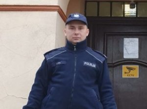 Na zdjęciu policjant w mundurze starszy sierżant Paweł Pyc stojący przed Komisariatem Policji w Twardogórze.
