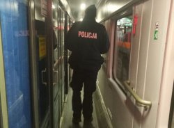 Na zdjęciu policjant kontrolujący przedziały w pociągu.