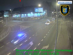 Zdjęcie z kamer monitoringu obrazujące skrzyżowania ulic Moniuszki Czarnieckiego w Legnicy. Na którym porusza się radiowóz oznakowany z włączonymi sygnałami świetlnymi oraz pojazd typu taxi.