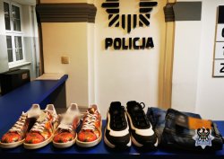 Na zdjęciu odzyskane przez policjantów mienie w postaci trzech par butów oraz spodni. W tle gwiazda policyjna.