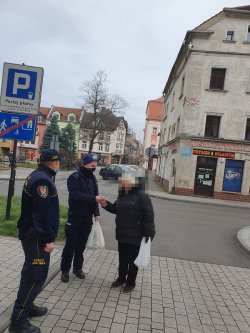 Na zdjęciu policjant i strażnik miejski rozmawiają na chodniku z seniorką.