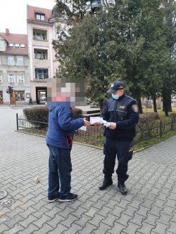 Na zdjęciu strażnik miejski rozmawia na chodniku z seniorem.