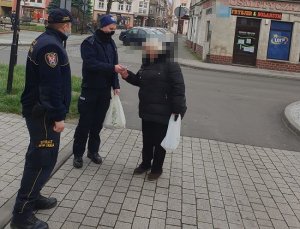 Na zdjęciu policjant i strażnik miejski rozmawiają na chodniku z seniorką.