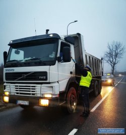 policjant kontroluje trzeźwość zatrzymanego kierowcy ciężarówki  przy pomocy alkomatu