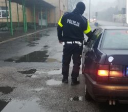 umundurowany policjant ruchu drogowego przy zatrzymanym samochodzie z alkomatem