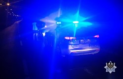 Na zdjęciu policjant stojący obok samochodu osobowego podczas jednej z nocnych kontroli drogowych.