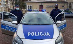 Na zdjęciu dwóch policjantów stojących przy radiowozie.