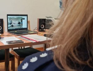 Na zdjęciu pokój w którym znajduje się policjantka obserwująca obraz na laptopie podczas spotkania online.
