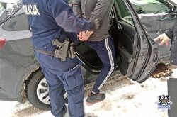 Na zdjęciu policjant wprowadza zatrzymanego do radiowozu.