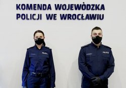 Na zdjęciu policjant i policjantka - biegli z laboratorium kryminalistycznego dolnośląskiej komendy, którzy  odebrali świadectwa potwierdzające ich uprawnienia. W tle napis Komenda Wojewódzka Policji we Wrocławiu.