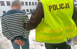 Na zdjęciu policjant prowadzi zatrzymanego mężczyznę.