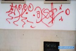Na zdjęciu ściana elewacyjna budynku ratusza. Pod oknami narysowane graffiti składające się z nic nie znaczących znaków koloru czerwonego.