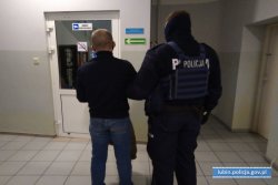 policjant prowadzi zatrzymanego mężczyznę do aresztu
