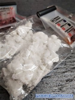 Zdjęcie przedstawia worki z białym proszkiem oraz tester narkotykowy.