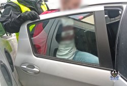 nie umundurowany policjant wsadza do nieoznakowanego mężczyznę w kajdankach