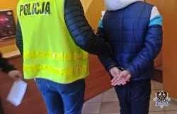 prowadzony przez policjanta mężczyzna w kajdankach