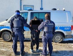 policjanci prowadzą do radiowozu zatrzymanego mężczyznę
