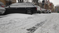 zaśnierzona ulica z parkingiem pełnym samochodów