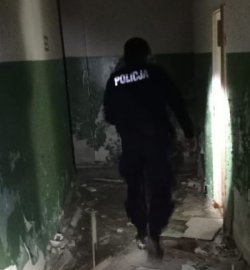 n zdjęciu widać policjanta sprawdzającego puste piwnice w opuszczonym budynku