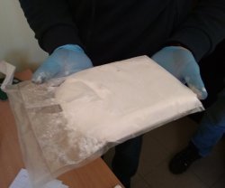 narkotyki w postacie białego proszku na rękach policjanta w niebieskich rękawiczkach