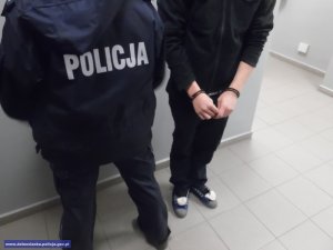 policjant z zatrzymanym mężczyzną stoją pod ścianą