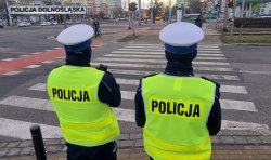 dwóch policjantów w białych czapkach i kamizelkach stoi przed przejsciem dla pieszych