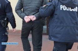 policjanci w mundurze prowadzą zatrzymanego mężczyznę w kajdankach